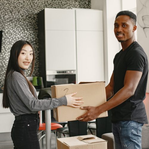 Portrait of young couple with cardboard boxes at new home, moving house concept.
